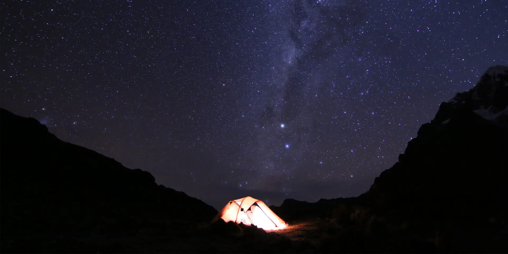 A tent is lit up in the night sky.