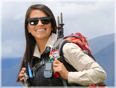A woman with sunglasses and backpack holding a cell phone.