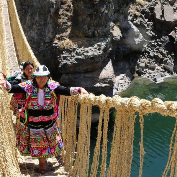 A woman in traditional dress crossing a bridge.