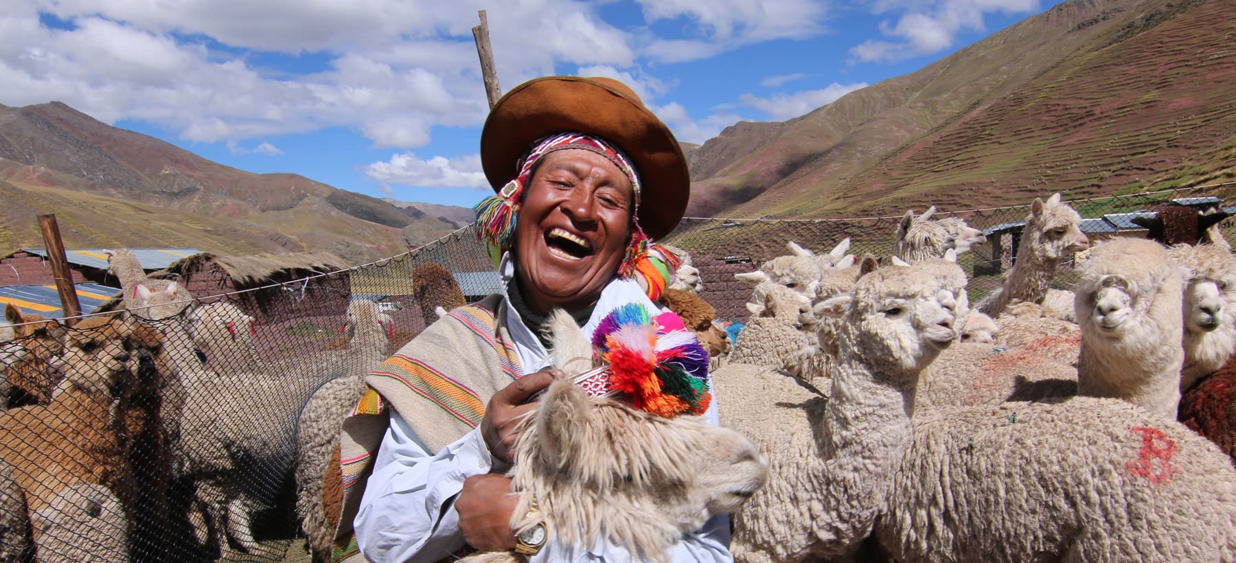 A man in traditional clothing holding a sheep.