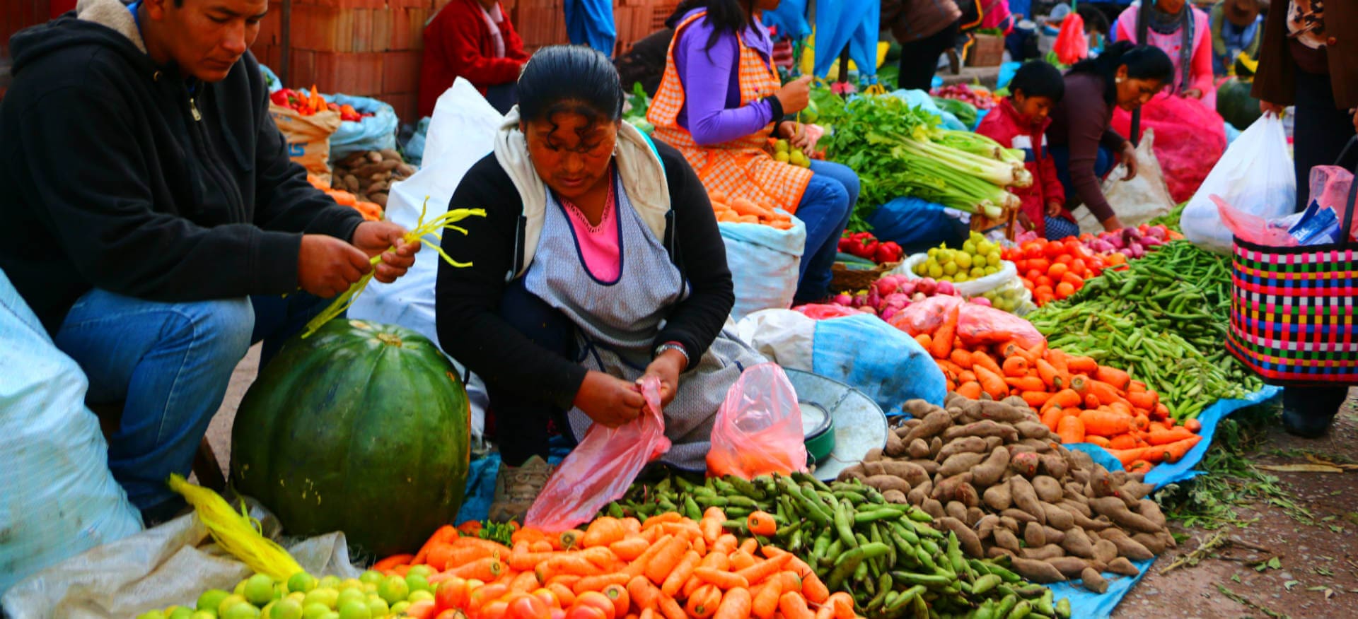 A woman sitting in front of many vegetables.