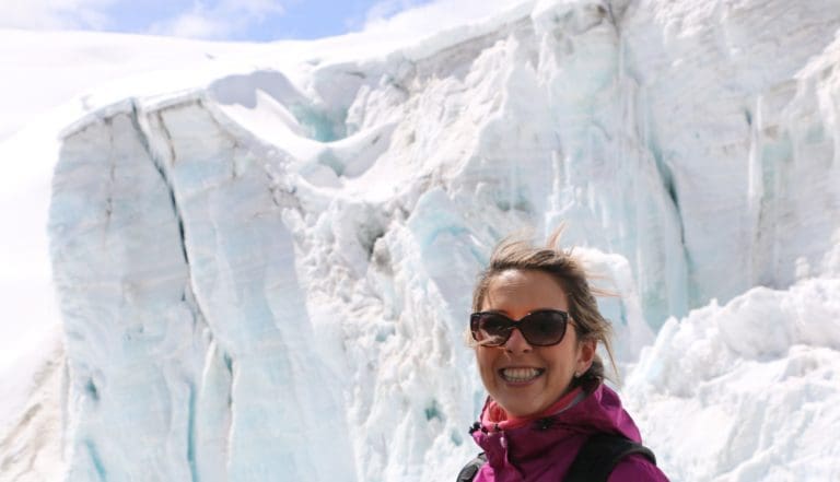 A woman standing in front of a large ice wall.