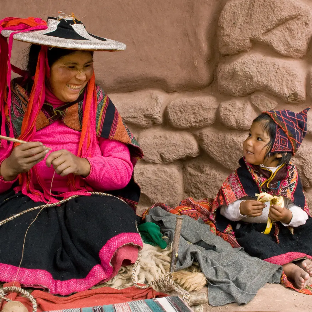 Two women sitting on the ground knitting.